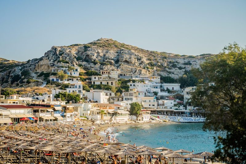 Illustration: A sandy beach with rows of parasols and hills behind