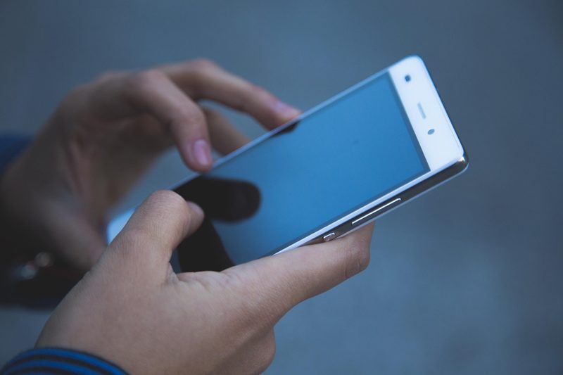 Illustration: A person using a smartphone with a blue screen