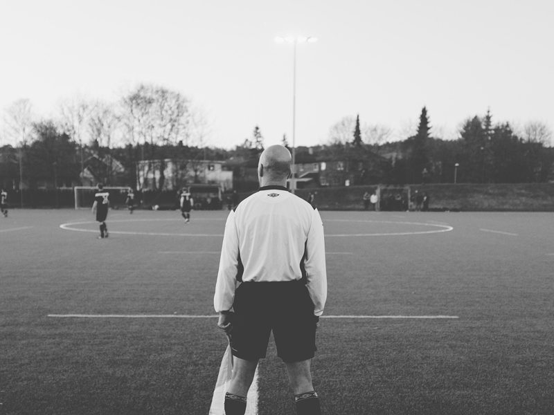 Illustration: A football referee standing on the pitch facing away