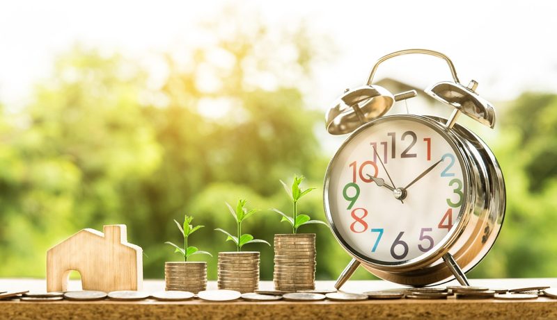 Illustration: An alarm clock, coin stacks with growing plants, and a house model