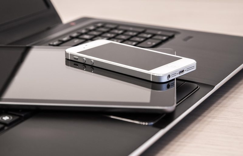 Illustration: A smartphone and a tablet rest on a laptop