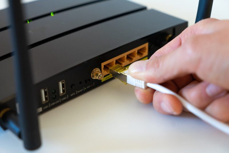 Illustration: A hand plugging an ethernet cable into a wireless router