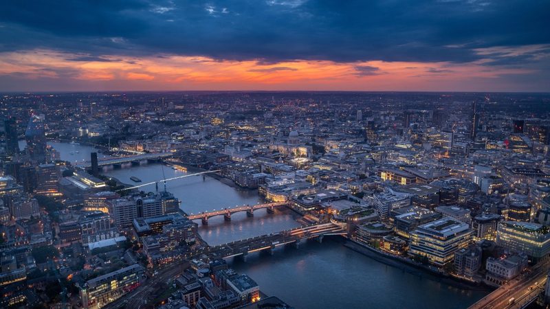 Illustration: Aerial view of a city along a river at sunset