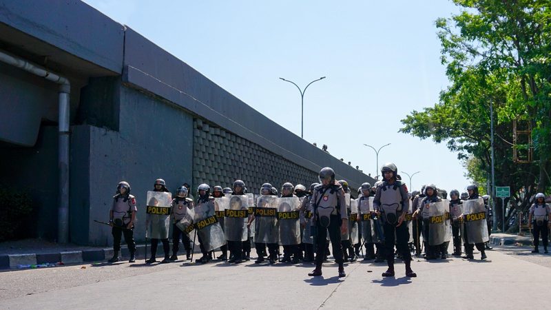 Illustration: A large line of police officers wearing riot gear standing together